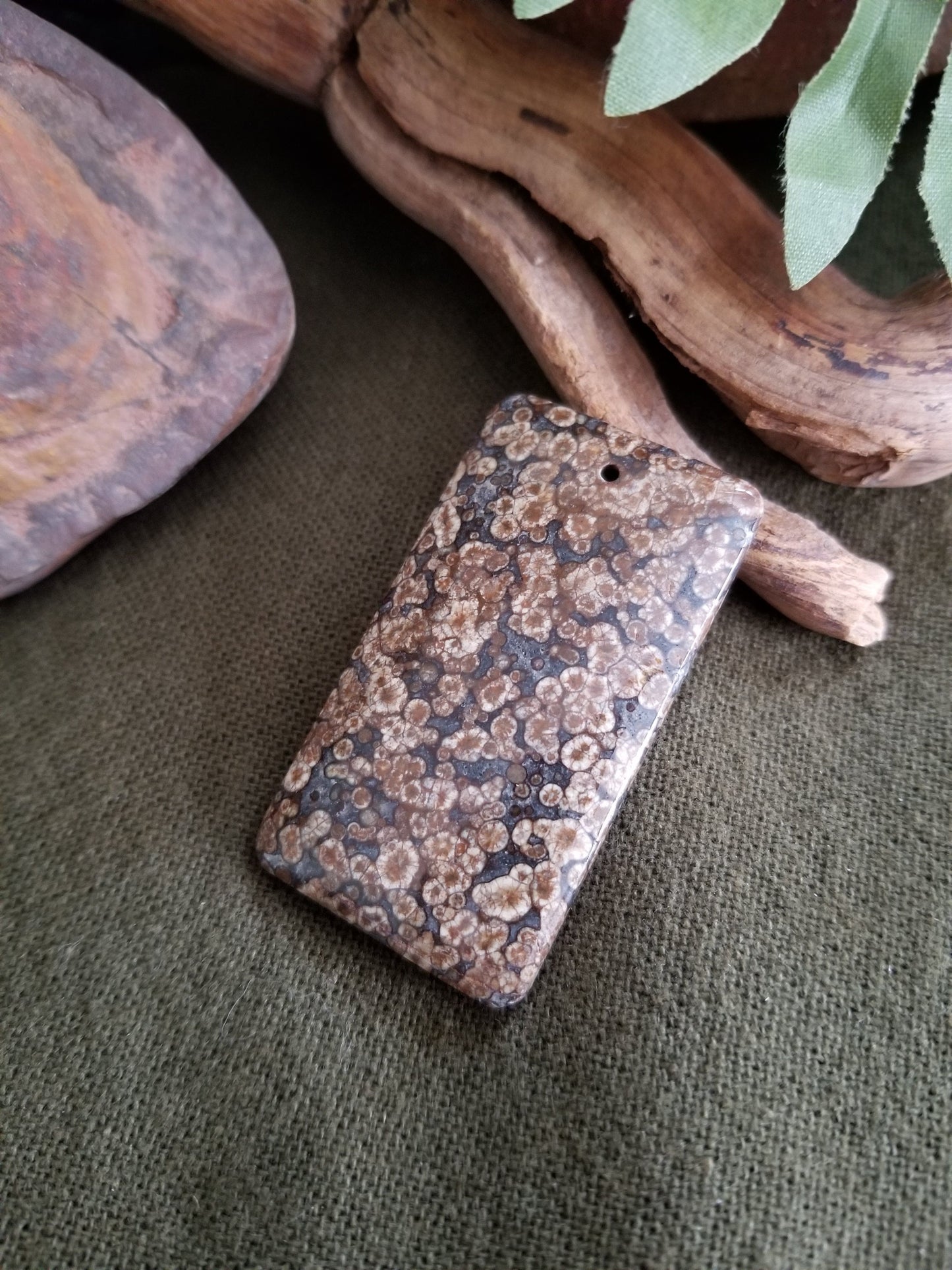 Fossilized coral rectangular bead with black, grey, and brown tones.