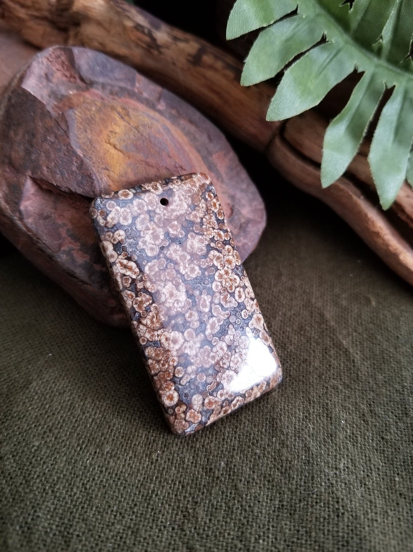 Fossilized coral rectangular bead with black, grey, and brown tones.
