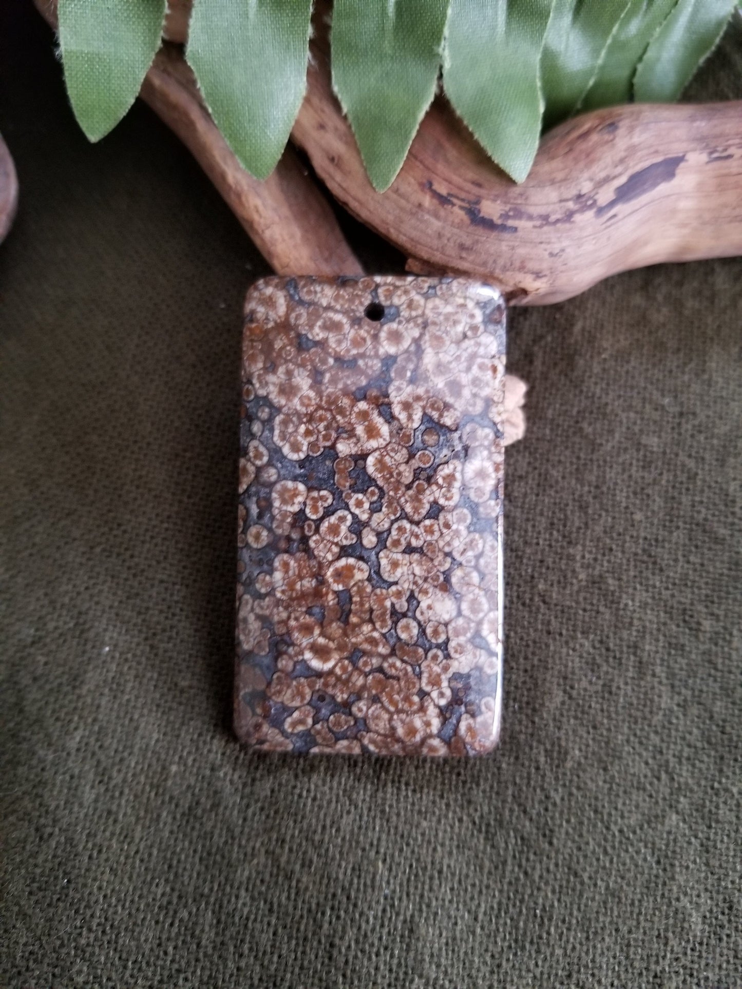 Fossilized coral rectangular bead with black, grey, and brown tones.