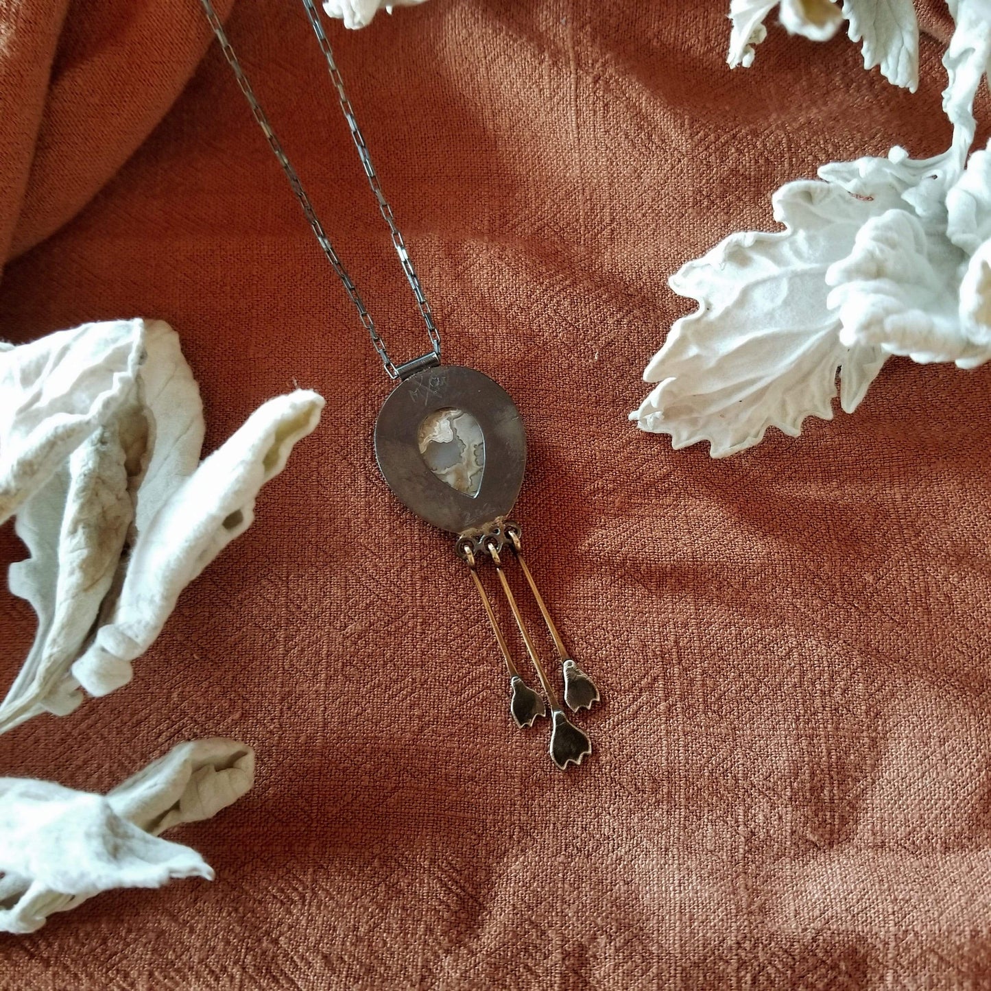 Back view of pendant with a teardrop cut out from the silver plate to reveal the stones patterns. Snowdrop Necklace No. 2 - Tear drop Mexican Agate (white and grey colors) set in sterling silver and brass with 3 individual hand engraved snowdrop flowers hanging from brass fringe. All hanging from a sterling silver box chain.