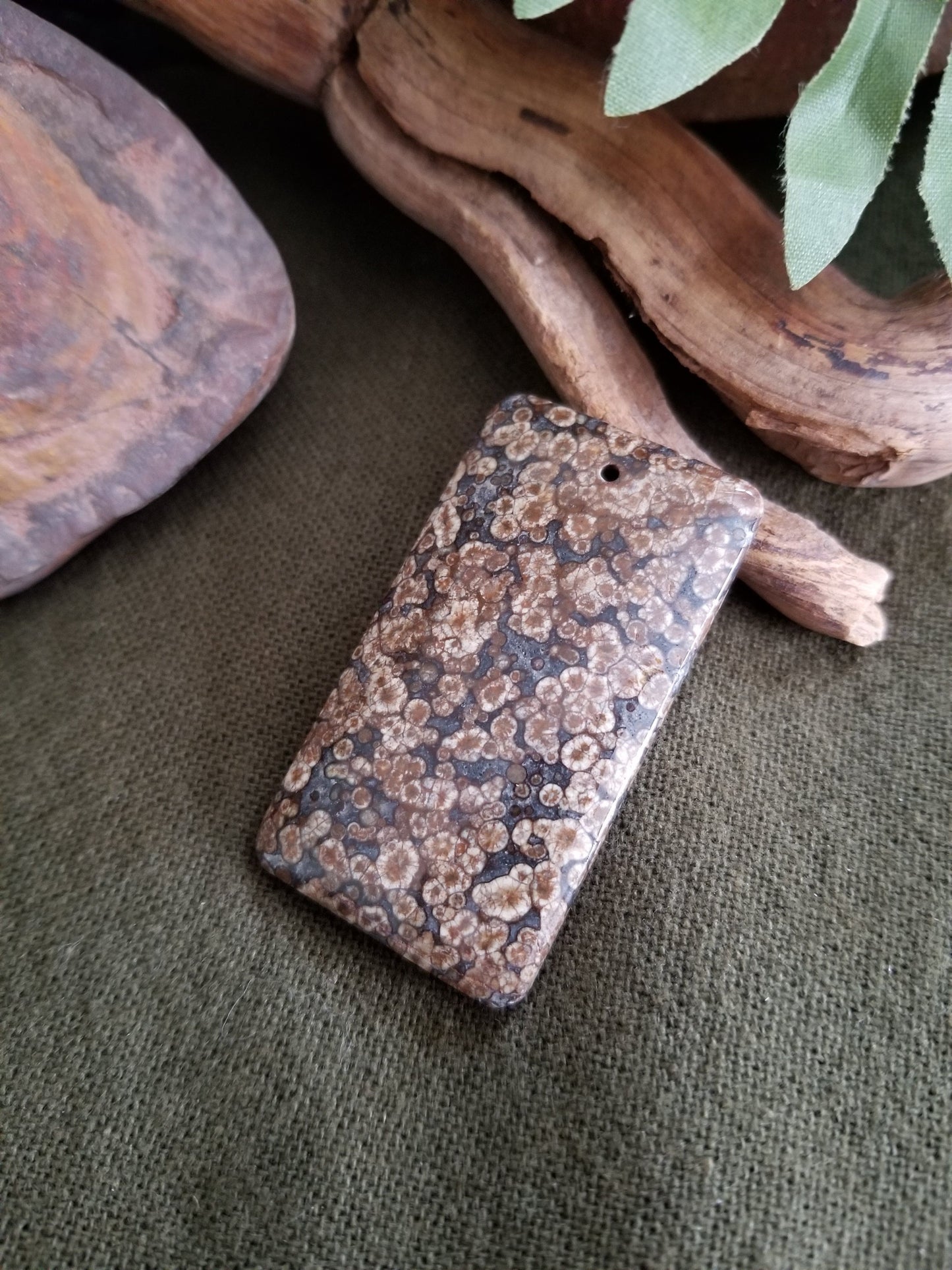 Fossilized coral rectangular bead with black, grey, and brown tones.