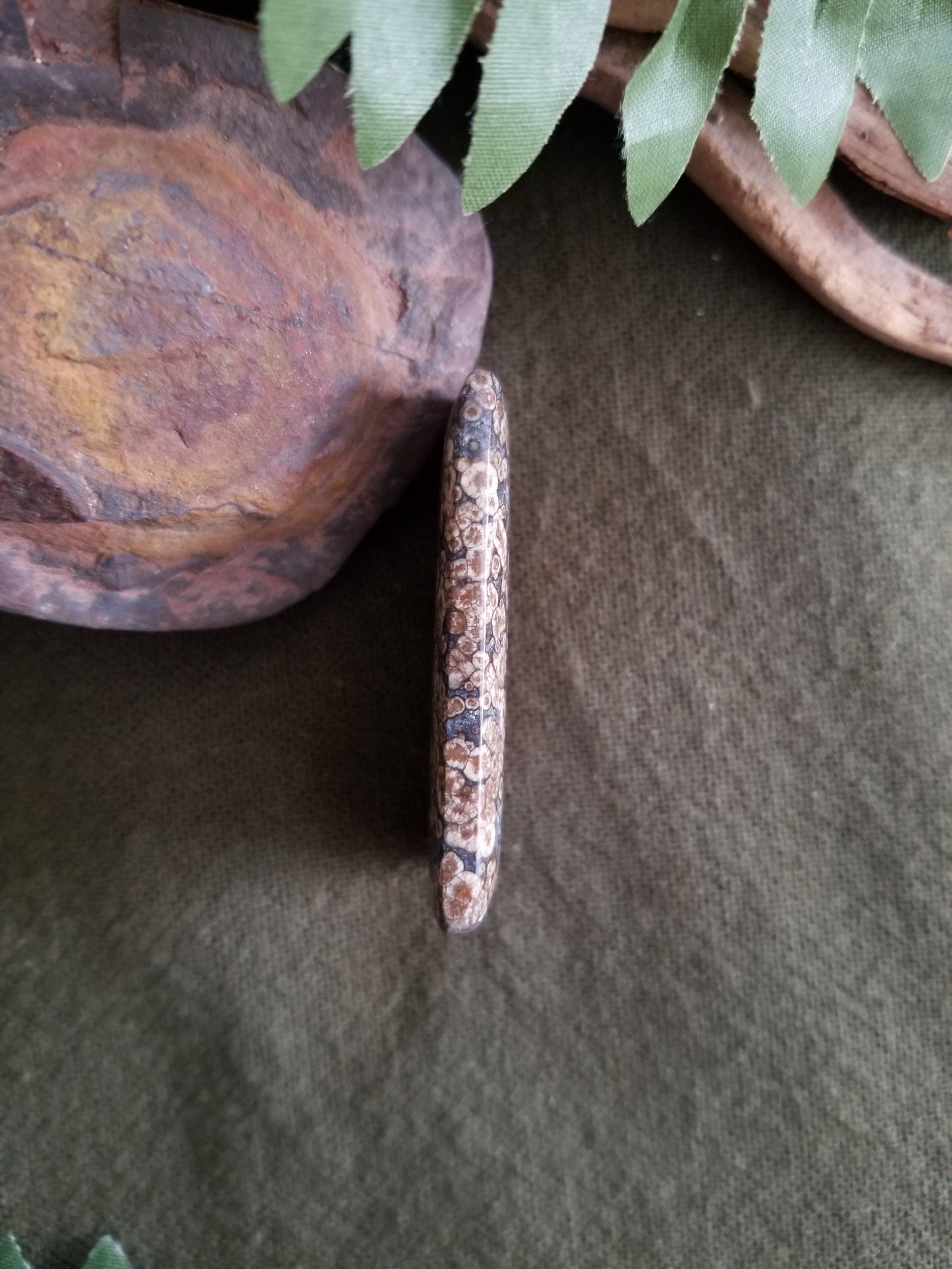 Fossilized coral rectangular bead with black, grey, and brown tones.