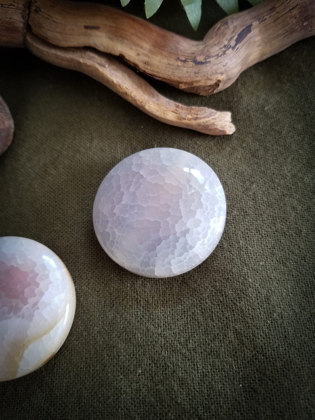 Close up. 2 Flat Round Agate beads. Color - translucent with tones of white, pink, and pale yellow. Smooth with a cracked effect created by heat.