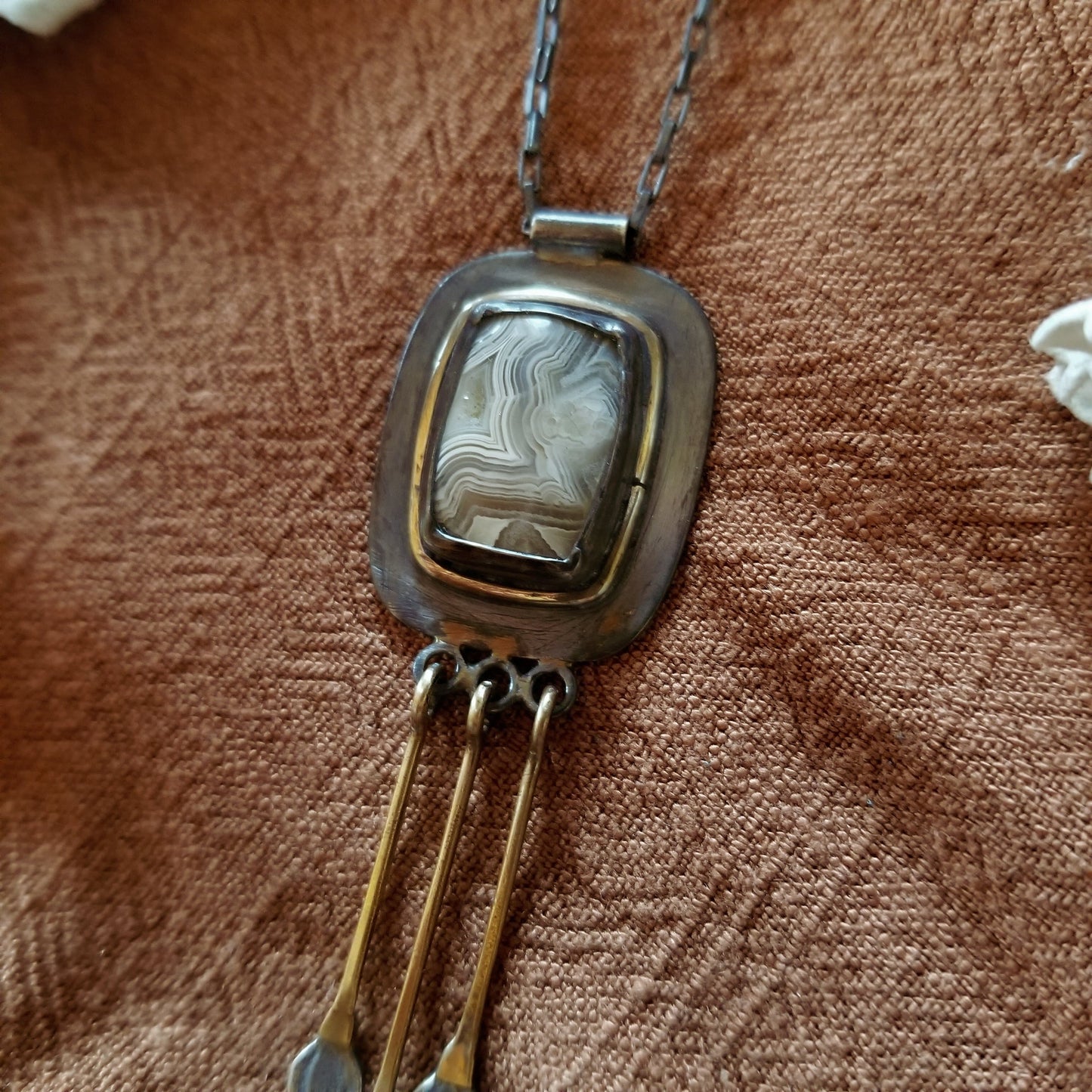 Close up of stone - banded agate pattern - white and greys - Snowdrop Necklace No. 1 - Cushion cut (rounded rectangle) Mexican Agate set in sterling silver and brass with 3 individual hand engraved snowdrop flowers hanging from brass fringe. All hanging from a sterling silver box chain. 