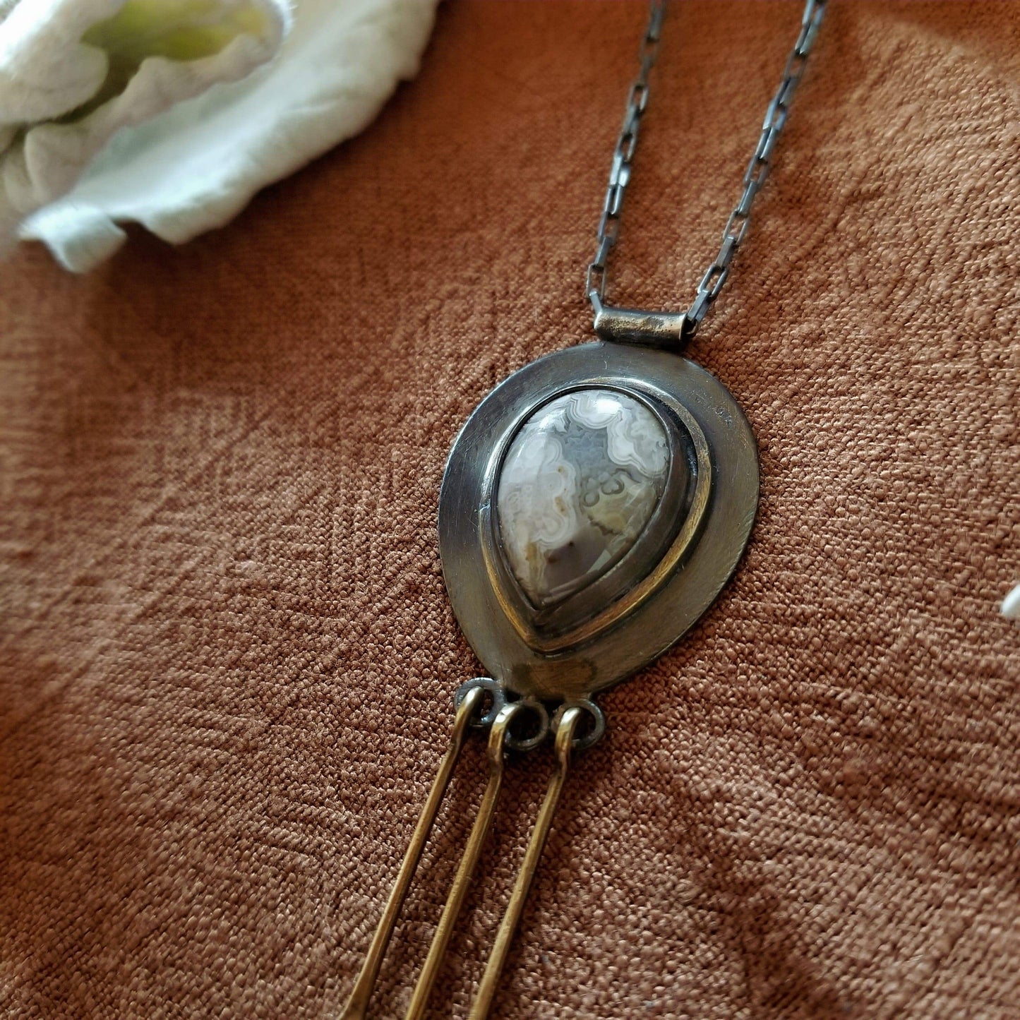 Close up of the bands in the Mexican Agate - Snowdrop Necklace No. 2 - Tear drop Mexican Agate (white and grey colors) set in sterling silver and brass with 3 individual hand engraved snowdrop flowers hanging from brass fringe. All hanging from a sterling silver box chain.