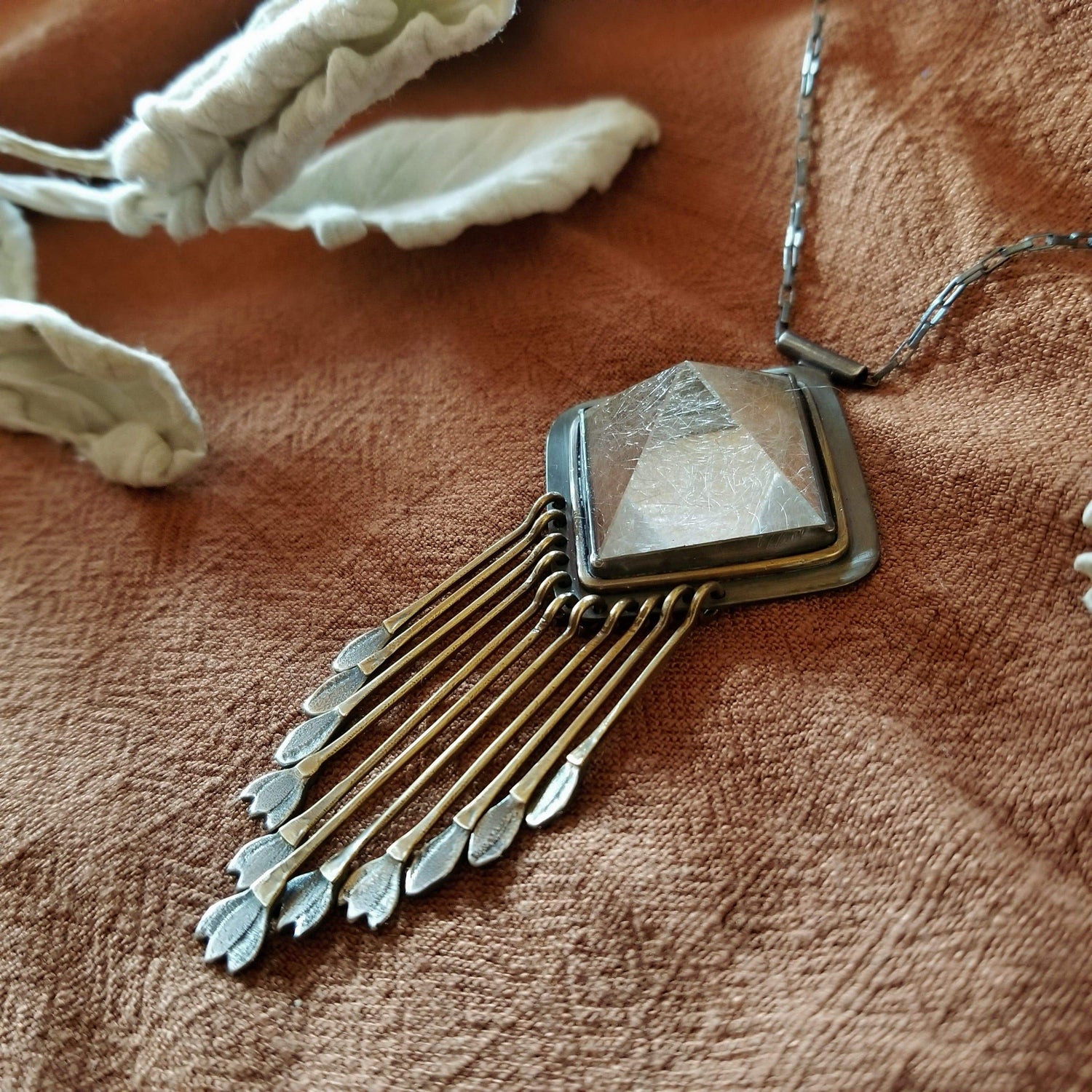 Handmade one of a kind necklace with rutilated quartz set in sterling silver and brass with eleven hand engraved snowdrop flower fringe dangles. All hanging on a sterling silver chain. 