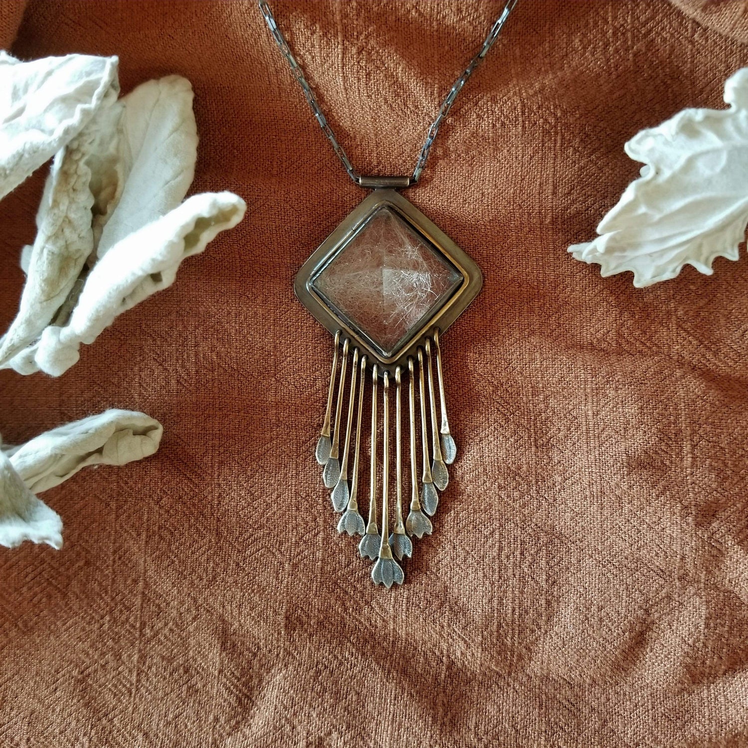 Handmade one of a kind necklace with rutilated quartz set in sterling silver and brass with eleven hand engraved snowdrop flower fringe dangles. All hanging on a sterling silver chain. 