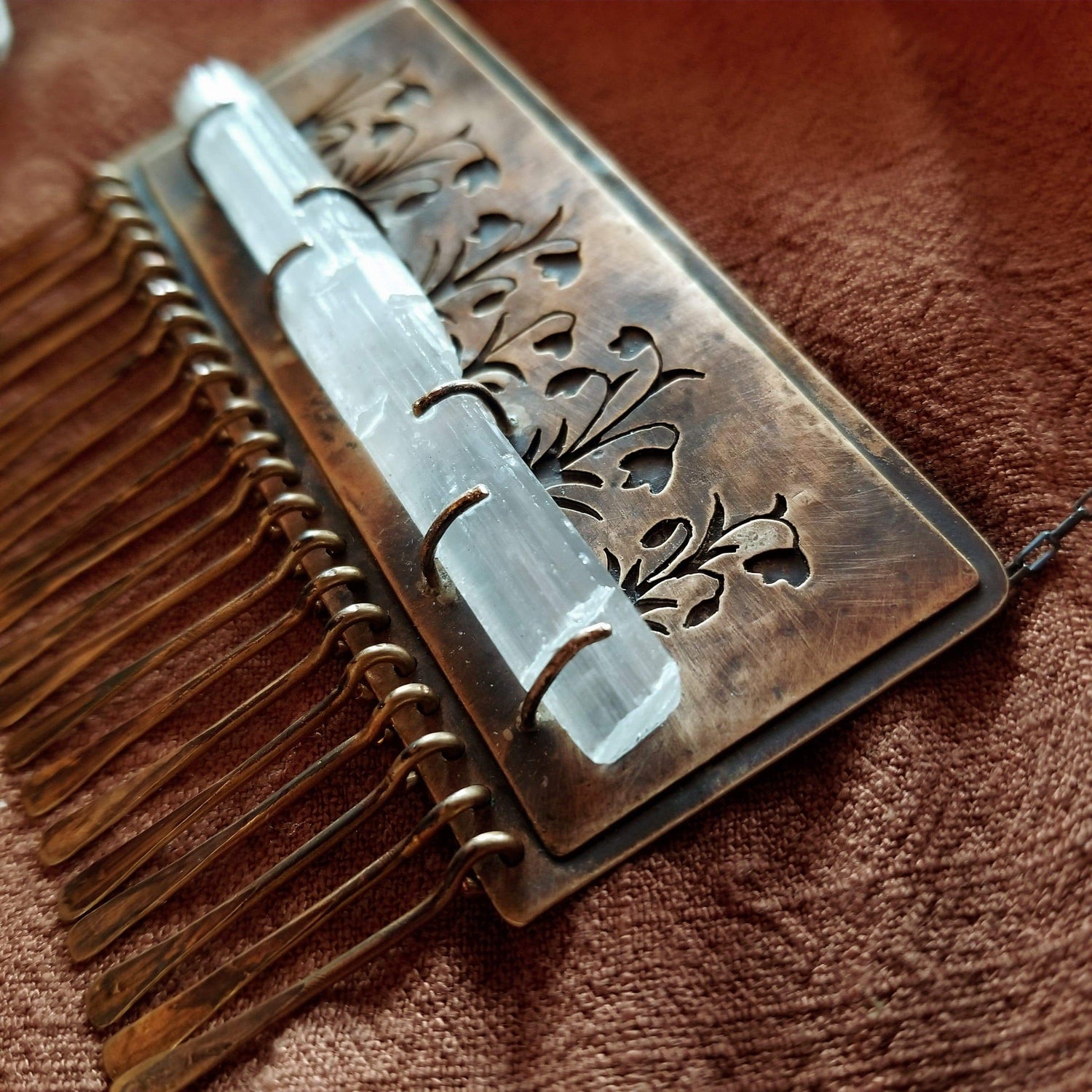 Handmade one of a kind necklace made with brass, sterling silver, and selenite. Brass is hand pierced with a meadow of snowdrop flowers sitting on top of a pronged set selenite wand. Hammered brass paddle fringe hang below. All hanging on a sterling silver chain.