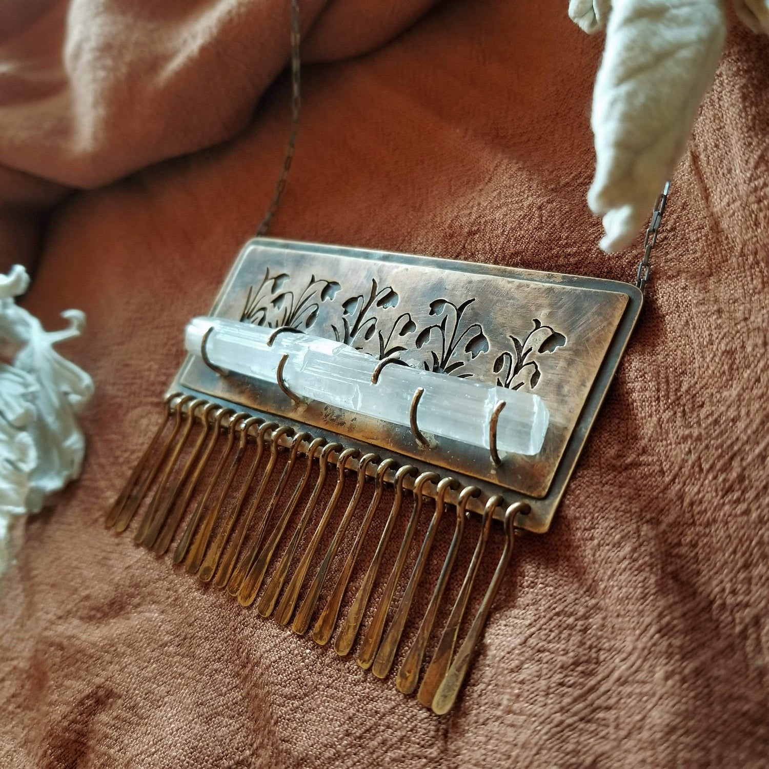 Handmade one of a kind necklace made with brass, sterling silver, and selenite. Brass is hand pierced with a meadow of snowdrop flowers sitting on top of a pronged set selenite wand. Hammered brass paddle fringe hang below. All hanging on a sterling silver chain.